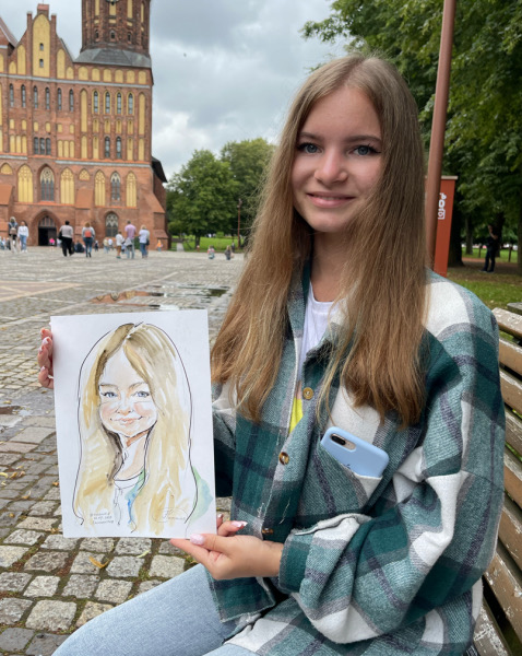 Наталья показывает шарж на острове Канта, шаржист Михаил Шабалин